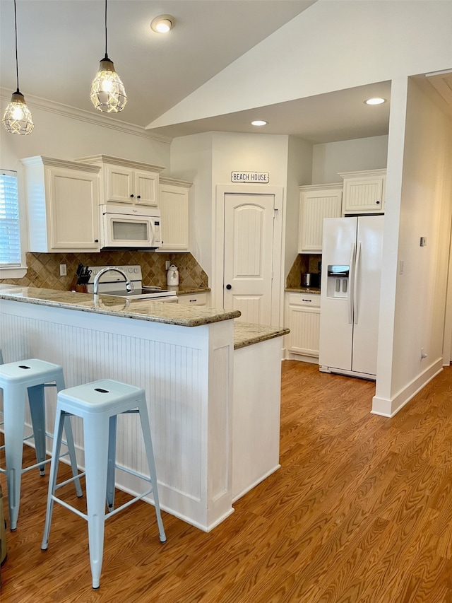 kitchen featuring light hardwood / wood-style flooring, hanging light fixtures, light stone countertops, and white appliances