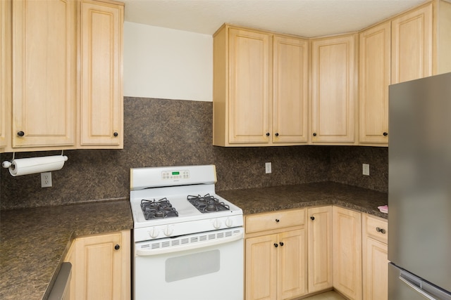 kitchen featuring backsplash, light brown cabinetry, stainless steel refrigerator, and white gas stove