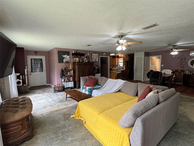 living area featuring visible vents, ceiling fan, a textured ceiling, and unfinished concrete floors