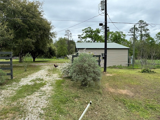 view of yard with an outbuilding, driveway, and fence