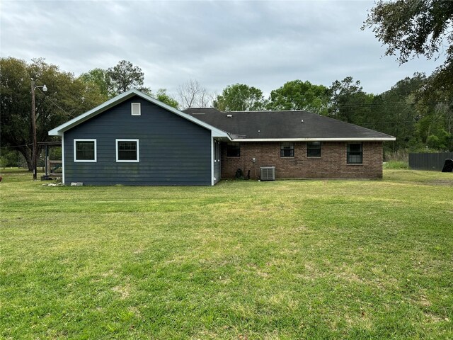 rear view of house featuring a lawn and central air condition unit