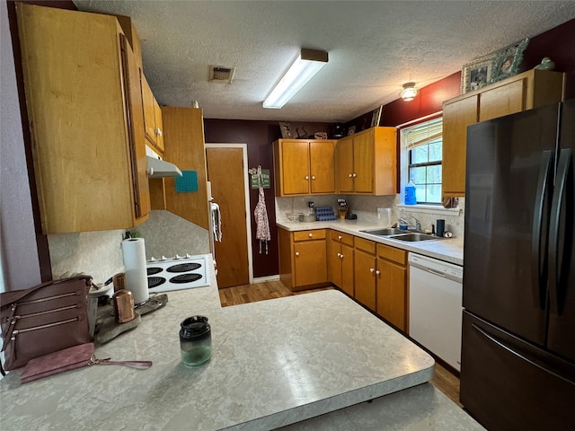 kitchen with black refrigerator, backsplash, sink, white dishwasher, and hardwood / wood-style flooring