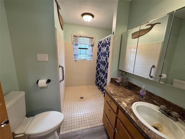 bathroom with a textured ceiling, a stall shower, vanity, and toilet