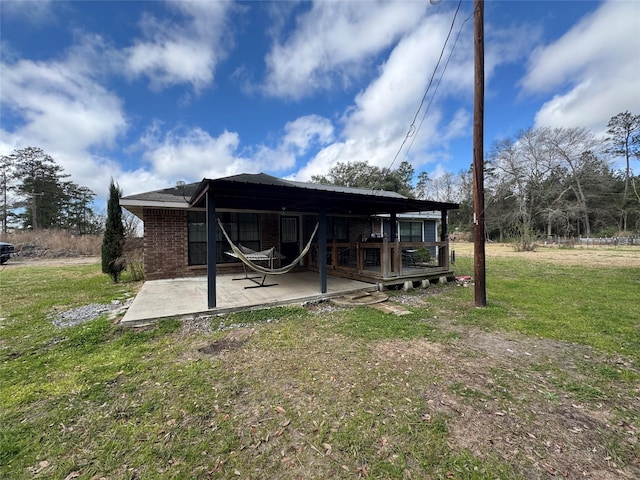 rear view of property featuring a yard, brick siding, and a patio