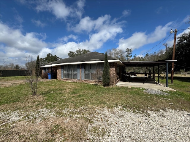 view of property exterior featuring a yard, a carport, brick siding, and driveway