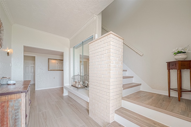 staircase featuring crown molding, a textured ceiling, and hardwood / wood-style floors