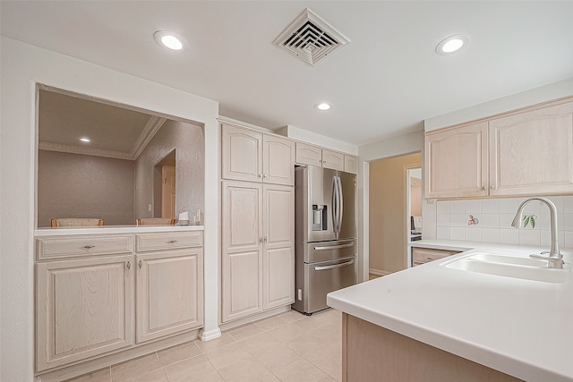 kitchen featuring decorative backsplash, light tile patterned floors, crown molding, stainless steel refrigerator with ice dispenser, and sink