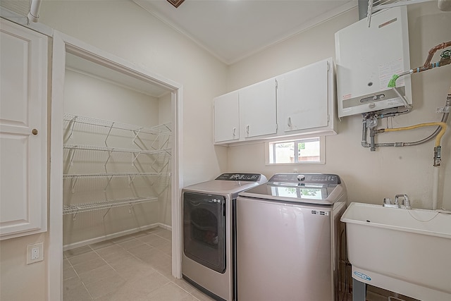 clothes washing area featuring sink, water heater, washer and clothes dryer, crown molding, and cabinets