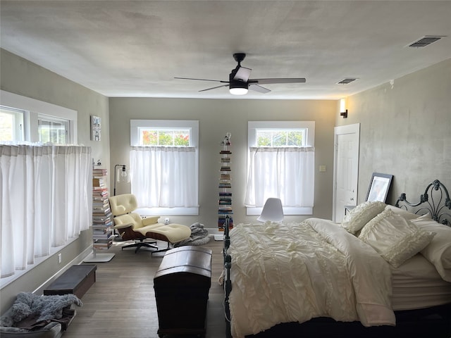 bedroom featuring ceiling fan, dark hardwood / wood-style flooring, and multiple windows