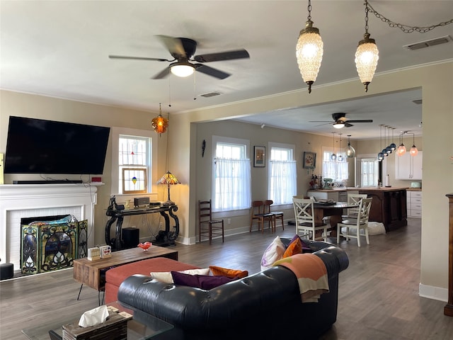 living room featuring ornamental molding, ceiling fan, dark hardwood / wood-style flooring, and a brick fireplace