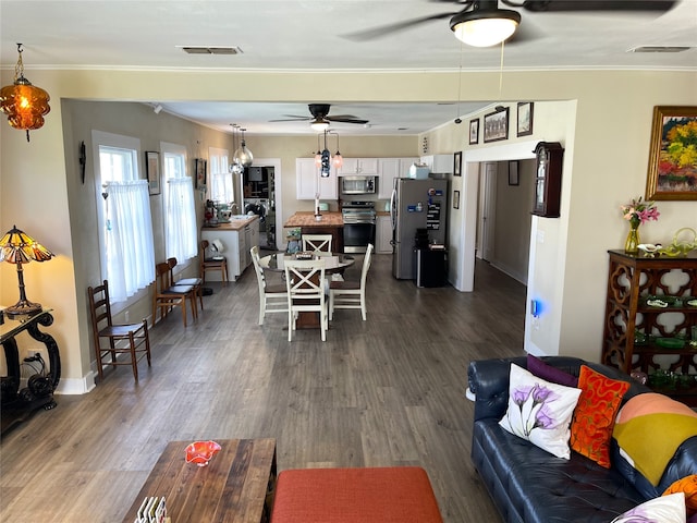 living room with ceiling fan, dark wood-type flooring, and crown molding