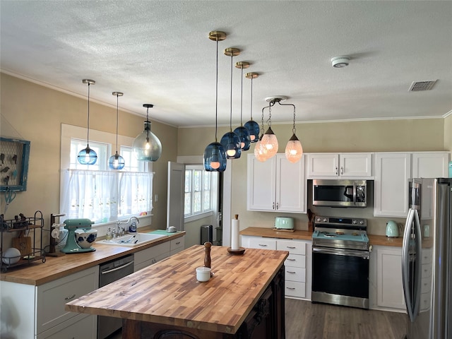 kitchen with wood counters, stainless steel appliances, decorative light fixtures, white cabinets, and dark hardwood / wood-style flooring