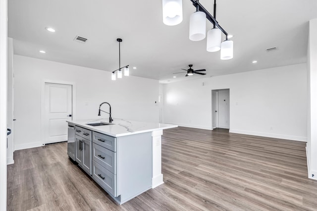 kitchen featuring sink, light hardwood / wood-style floors, pendant lighting, gray cabinets, and a kitchen island with sink