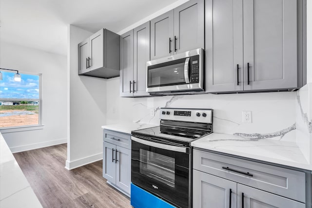 kitchen featuring light stone counters, gray cabinetry, stainless steel appliances, and dark hardwood / wood-style floors