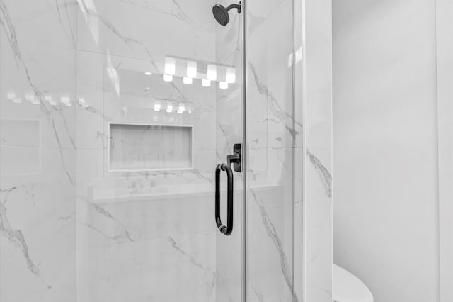 bathroom with a shower with door and toilet