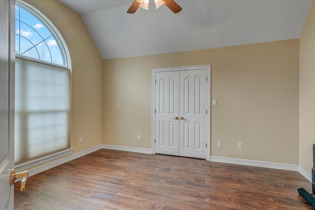 empty room with ceiling fan, vaulted ceiling, and dark wood-type flooring