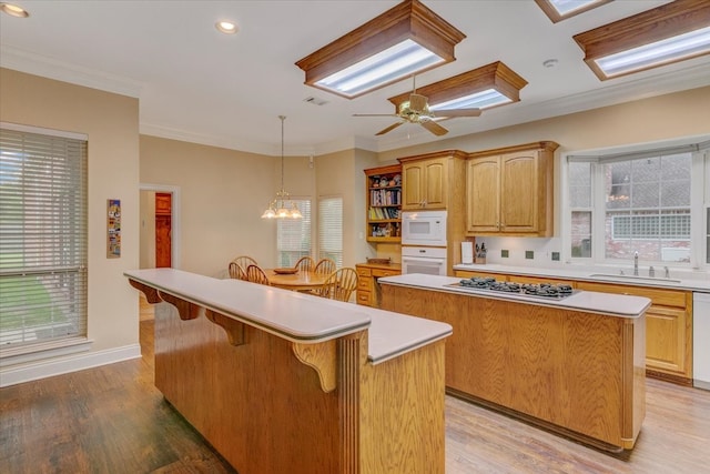 kitchen featuring a kitchen island, a kitchen bar, plenty of natural light, white appliances, and ceiling fan with notable chandelier