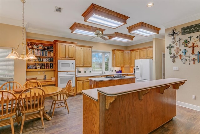 kitchen with a kitchen island, dark hardwood / wood-style floors, white appliances, ceiling fan with notable chandelier, and a kitchen breakfast bar