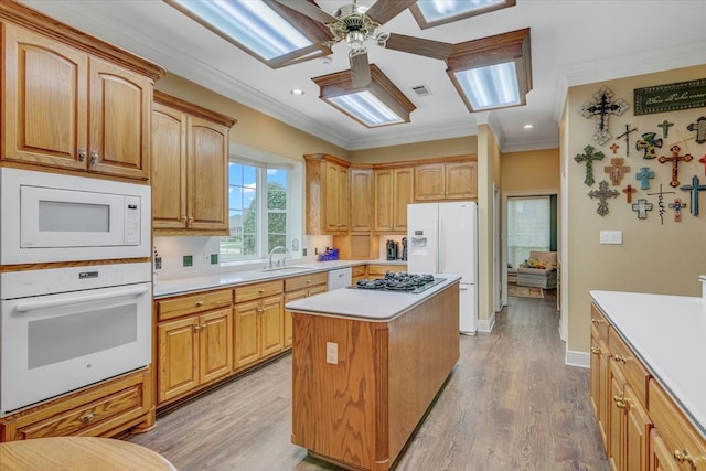 kitchen with light hardwood / wood-style floors, a kitchen island, crown molding, ceiling fan, and white appliances