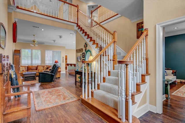 stairs with dark hardwood / wood-style flooring, ceiling fan, and crown molding