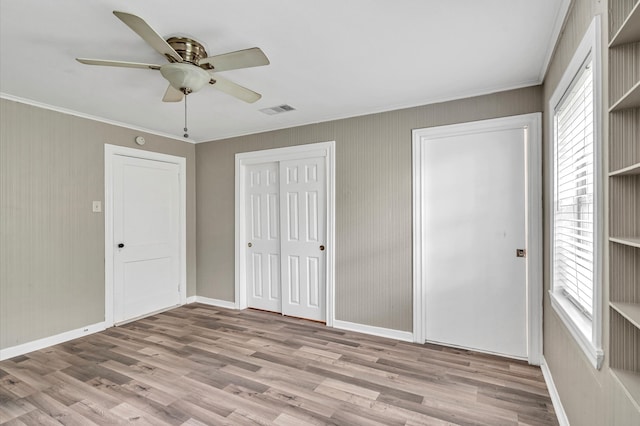 unfurnished bedroom featuring ceiling fan, crown molding, hardwood / wood-style flooring, and multiple windows