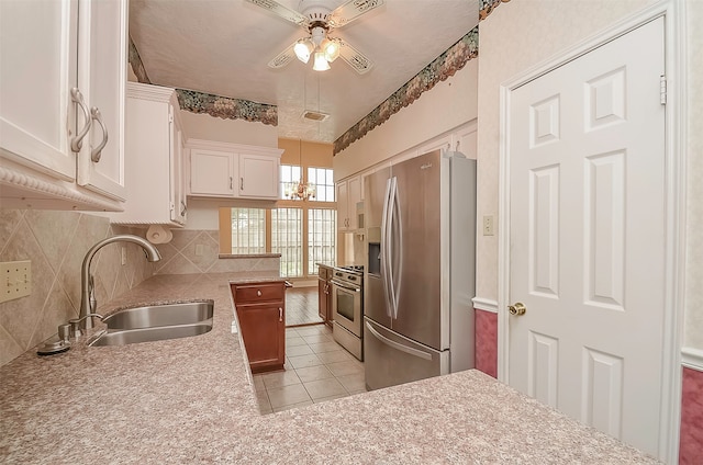 kitchen with stainless steel fridge, sink, stove, light tile flooring, and ceiling fan with notable chandelier