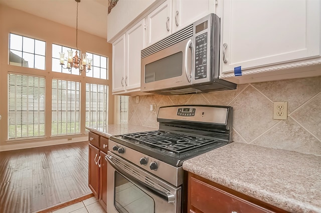 kitchen featuring stainless steel appliances, tasteful backsplash, white cabinetry, and a notable chandelier