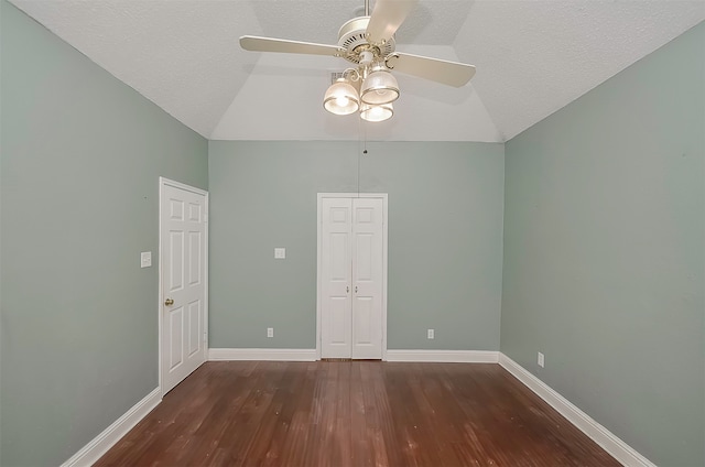 empty room featuring a textured ceiling, vaulted ceiling, ceiling fan, and dark hardwood / wood-style flooring