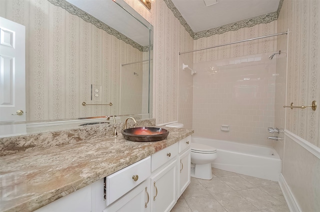 full bathroom featuring toilet, tile flooring, tiled shower / bath, and vanity with extensive cabinet space