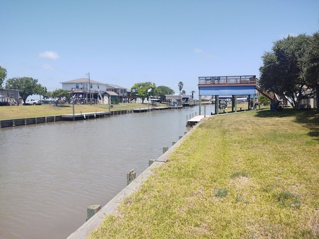 view of dock with a water view and a lawn