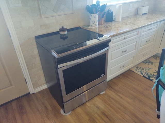 kitchen featuring white cabinets, dark hardwood / wood-style floors, range with electric cooktop, and light stone countertops