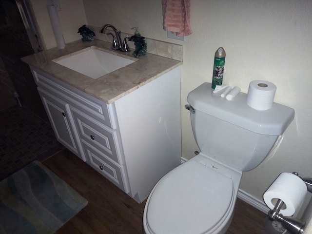 bathroom with toilet, vanity, and hardwood / wood-style flooring