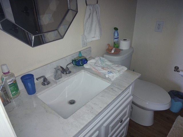 bathroom with toilet, vanity, and wood-type flooring