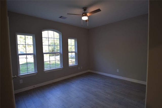 empty room with a healthy amount of sunlight, ceiling fan, and dark hardwood / wood-style floors