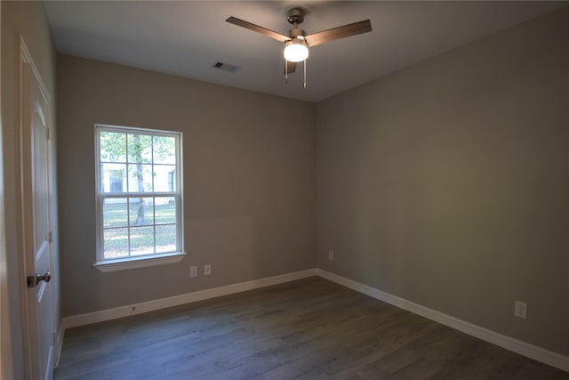 empty room with a healthy amount of sunlight, ceiling fan, and dark wood-type flooring