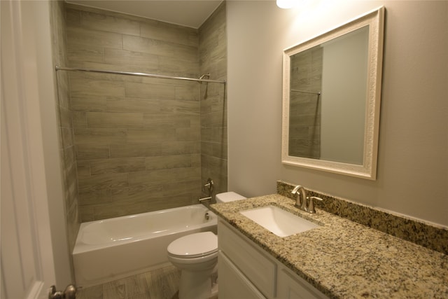 full bathroom featuring tiled shower / bath, toilet, wood-type flooring, and vanity with extensive cabinet space