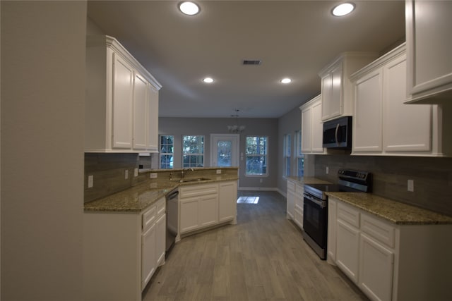 kitchen featuring appliances with stainless steel finishes, a chandelier, white cabinets, kitchen peninsula, and light wood-type flooring