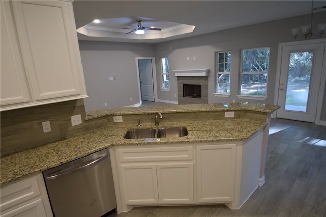 kitchen featuring dark wood-type flooring, white cabinetry, dishwasher, ceiling fan with notable chandelier, and a tray ceiling