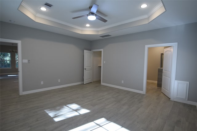 unfurnished bedroom featuring ornamental molding, a tray ceiling, ceiling fan, and light hardwood / wood-style flooring