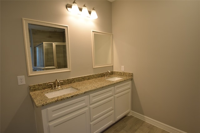 bathroom with dual vanity, a shower with door, and hardwood / wood-style floors