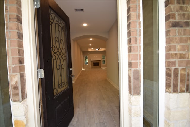 hallway featuring brick wall and hardwood / wood-style flooring