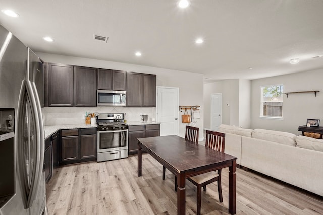 kitchen featuring light wood-type flooring, dark brown cabinetry, tasteful backsplash, and appliances with stainless steel finishes