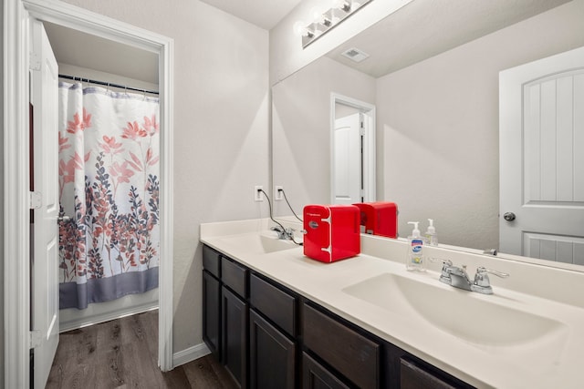 bathroom with double sink, hardwood / wood-style floors, and vanity with extensive cabinet space