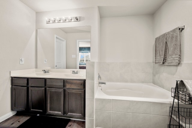 bathroom with tiled bath, vanity, and hardwood / wood-style flooring