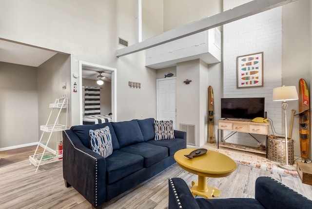 living room featuring ceiling fan, a towering ceiling, and wood-type flooring