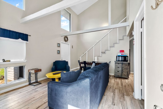 living room featuring high vaulted ceiling and light hardwood / wood-style flooring