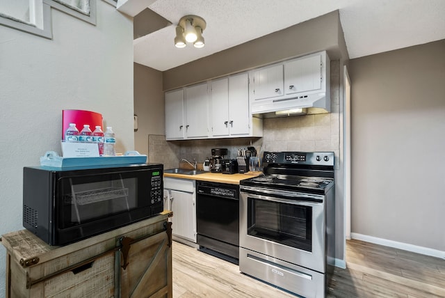 kitchen with light wood-type flooring, black appliances, white cabinets, and backsplash