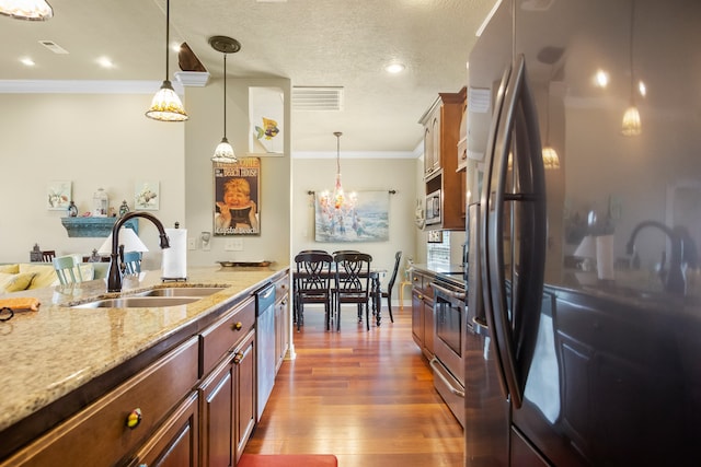 kitchen featuring appliances with stainless steel finishes, hanging light fixtures, a chandelier, light stone countertops, and dark hardwood / wood-style floors