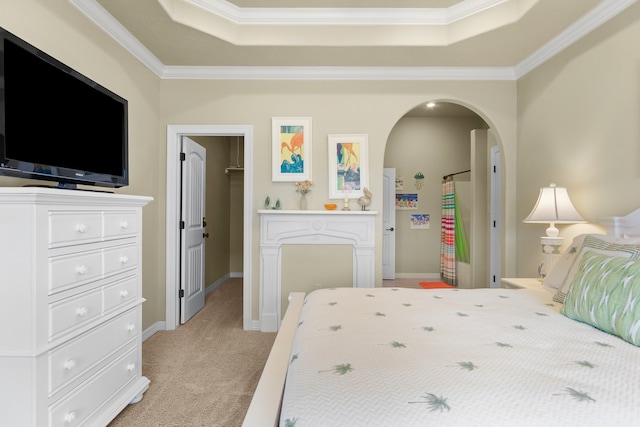 carpeted bedroom featuring crown molding, a walk in closet, and a tray ceiling