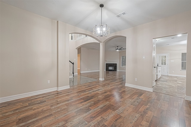 unfurnished dining area featuring ceiling fan with notable chandelier and hardwood / wood-style flooring